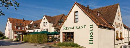 Traditionelles Hotelgebäude mit rotem Dach, heller Fassade und Restaurantaufschrift.