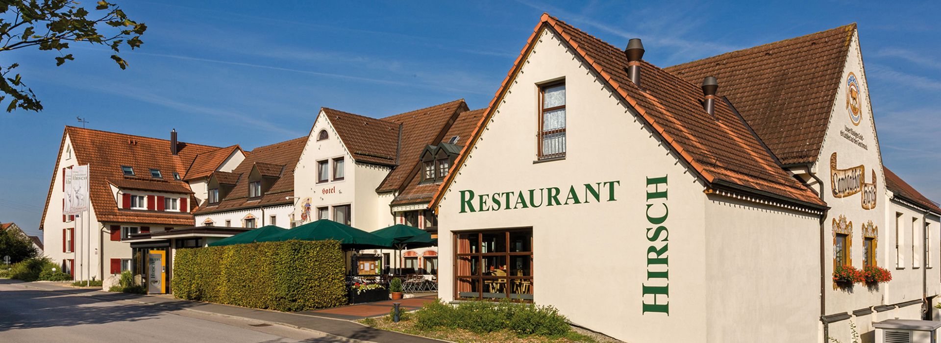 Traditionelles Hotelgebäude mit rotem Dach, heller Fassade und Restaurantaufschrift.