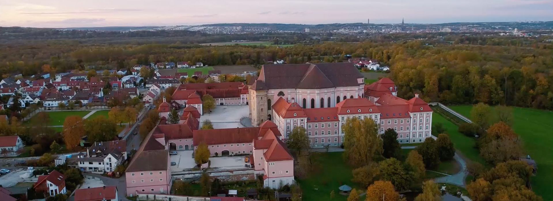  Luftaufnahme des Klosters Wiblingen mit barocker Klosterkirche, umgeben von herbstlicher Landschaft.