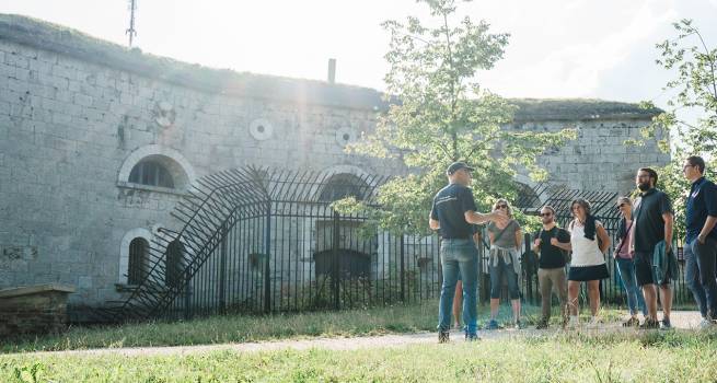 Gruppe bei Führung vor dem Haupttor der Bundesfestung Wilhelmsburg bei Sonnenschein.