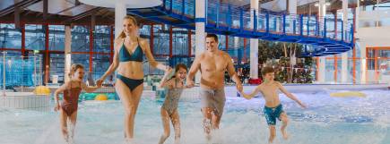 Familie mit Kindern läuft lachend durch das Erlebnisbecken im Freizeitbad Donaubad.