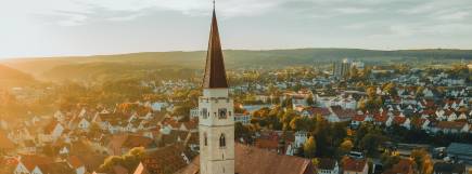Stadtpanorama mit Kirchturm von Ehingen bei Sonnenuntergang, Blick über Dächer und Landschaft.